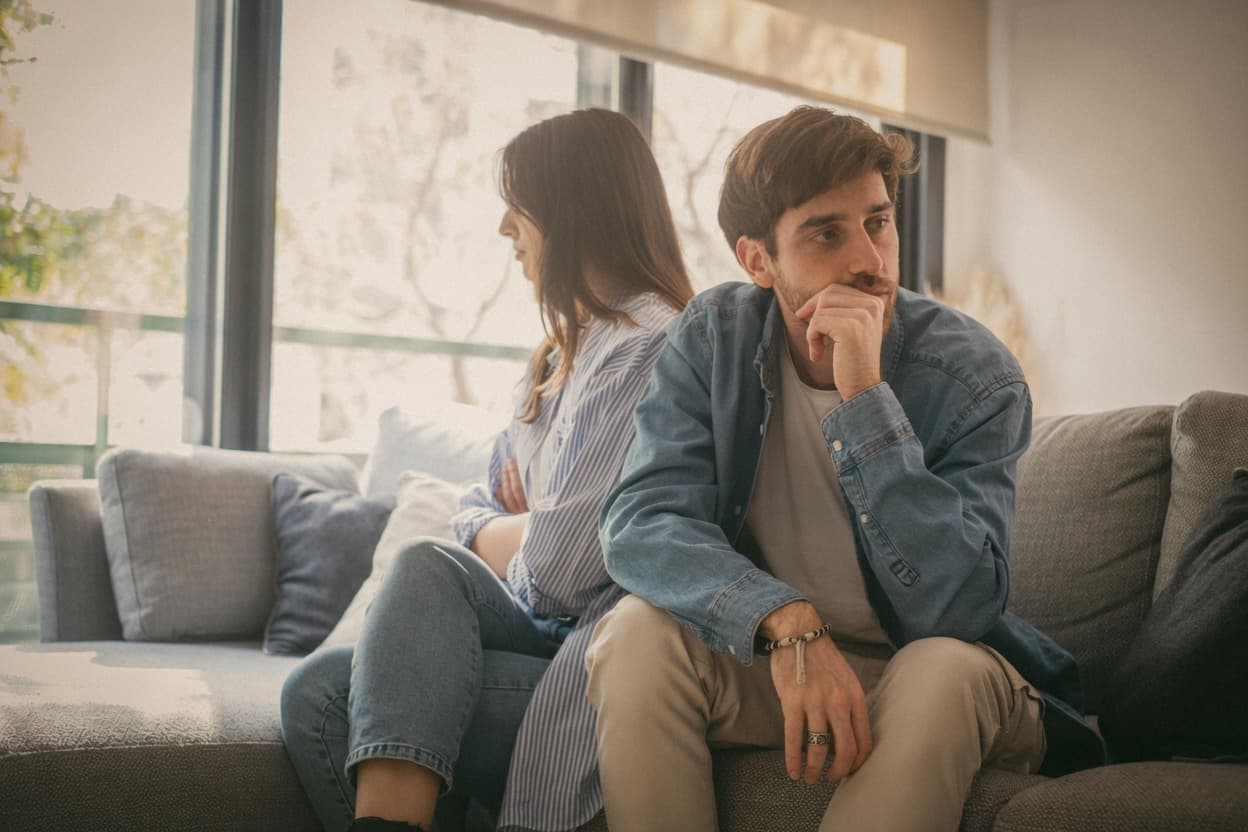 A couple sitting apart on a couch, caught in the same loop