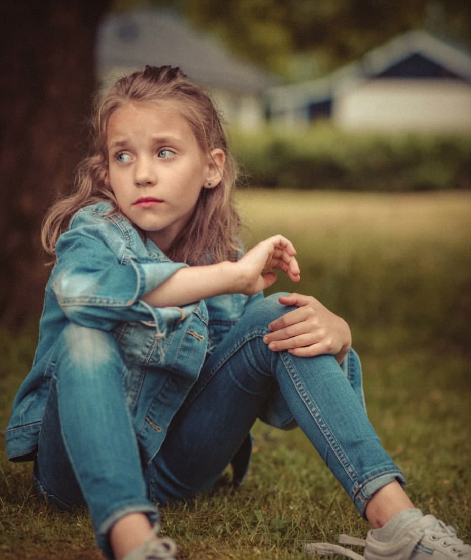 A young girl sitting quietly outdoors